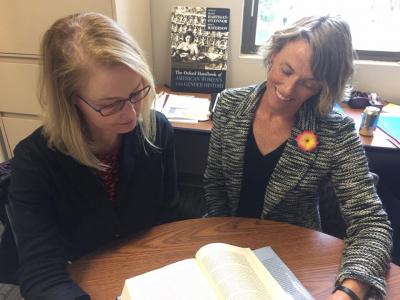 Two UC Davis historians sitting at a table, looking at a book.