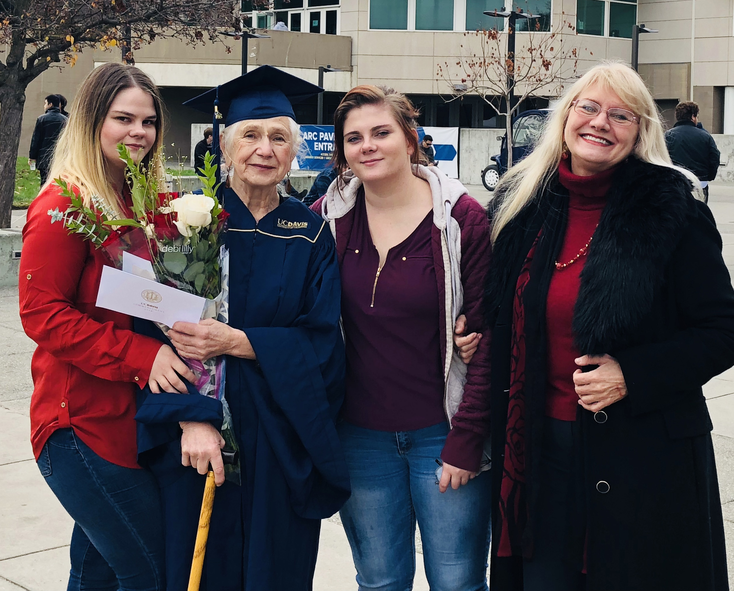 Photo of Marianna Daniel in cap and gown with her family in front of the UC Davis ARC Pavilion