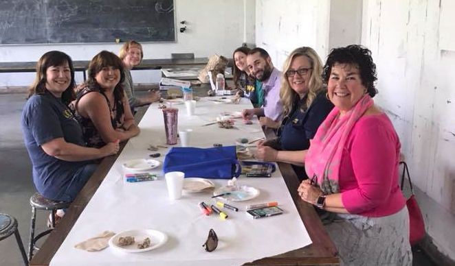 Group of people around a table with paint and rocks