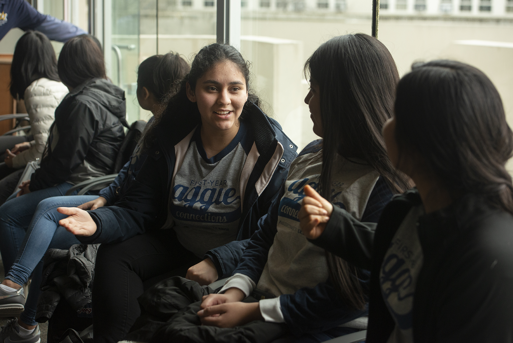 A Latinx student chats with two female classmates in a UC Davis first-year seminar.