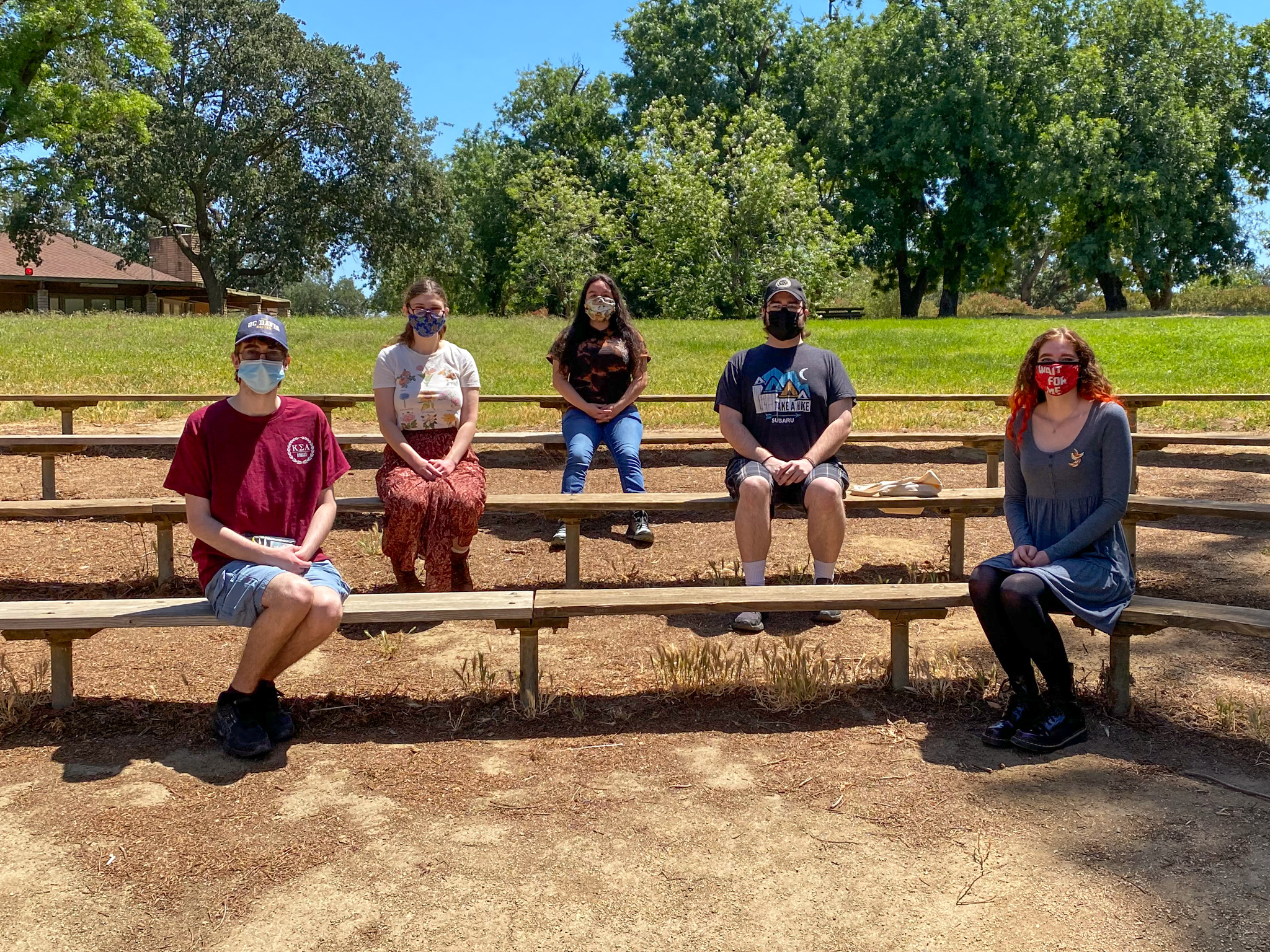 Five students wearing face masks and sitting on outdoor theater benches
