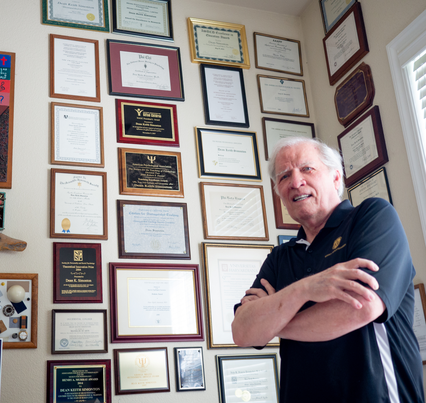 Dean Keith Simonton stands by a wall of awards in his home.