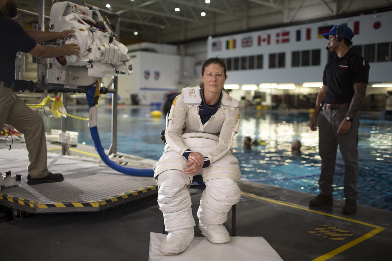 Tracy Dyson is wearing her space suit and sitting in front of an indoor pool