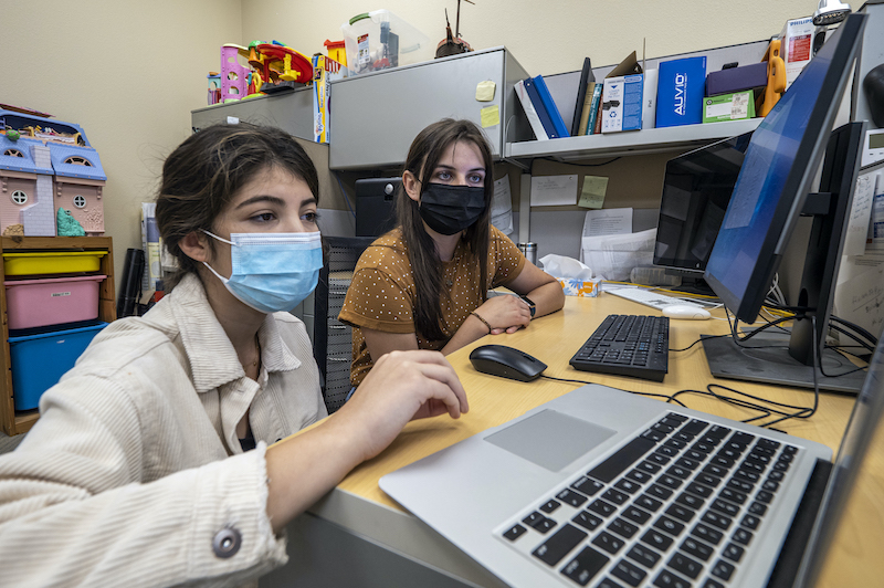 Two student researchers look at a laptop on a desk in the UC Davis Center for Mind and Brain