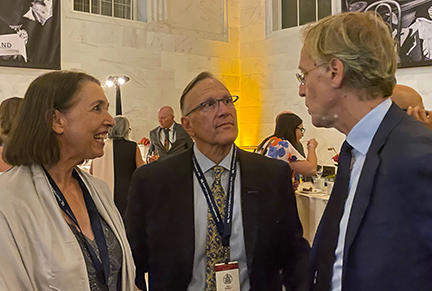 Woman and two men chat at a reception.