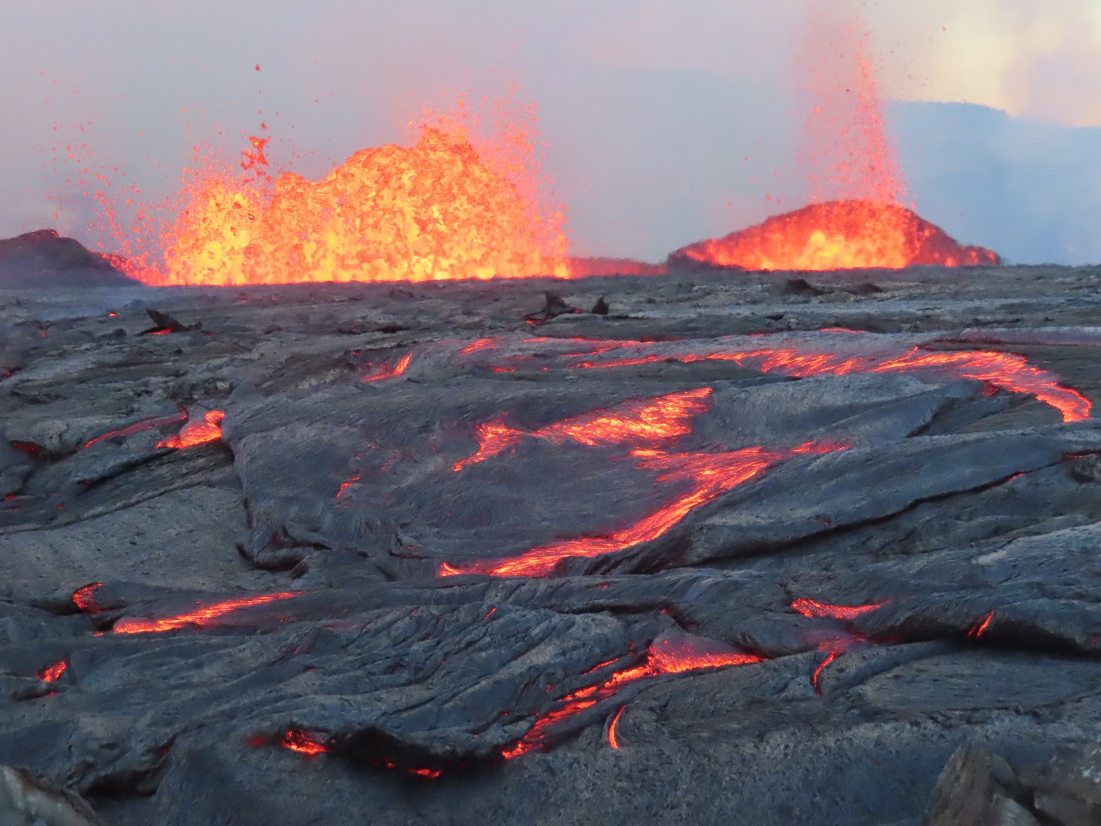 A volcano is erupting with bright, orange lava coming up from the ground