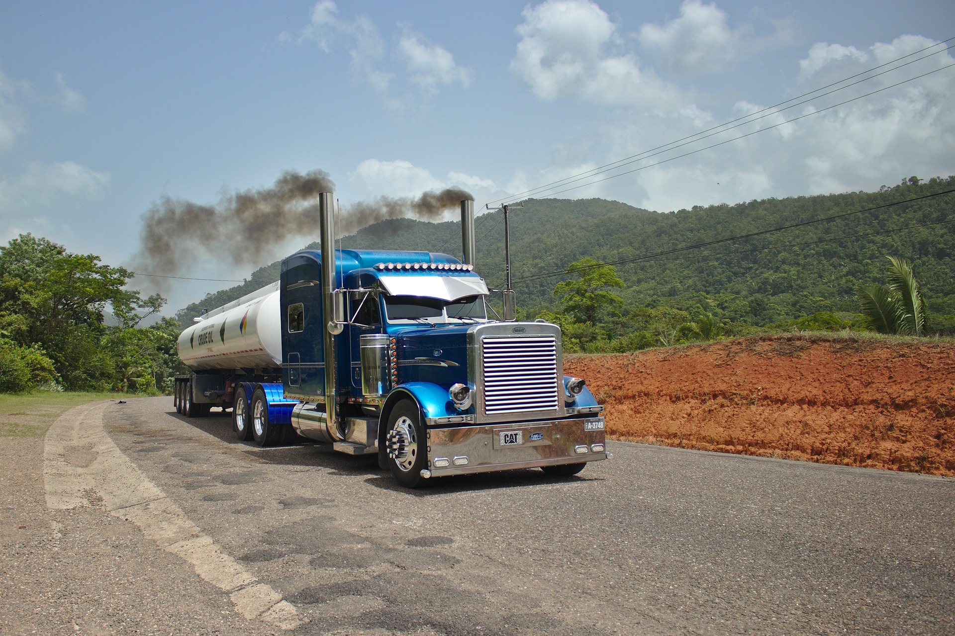 Semi-truck on roadway, smoke coming from exhaust pipes on top