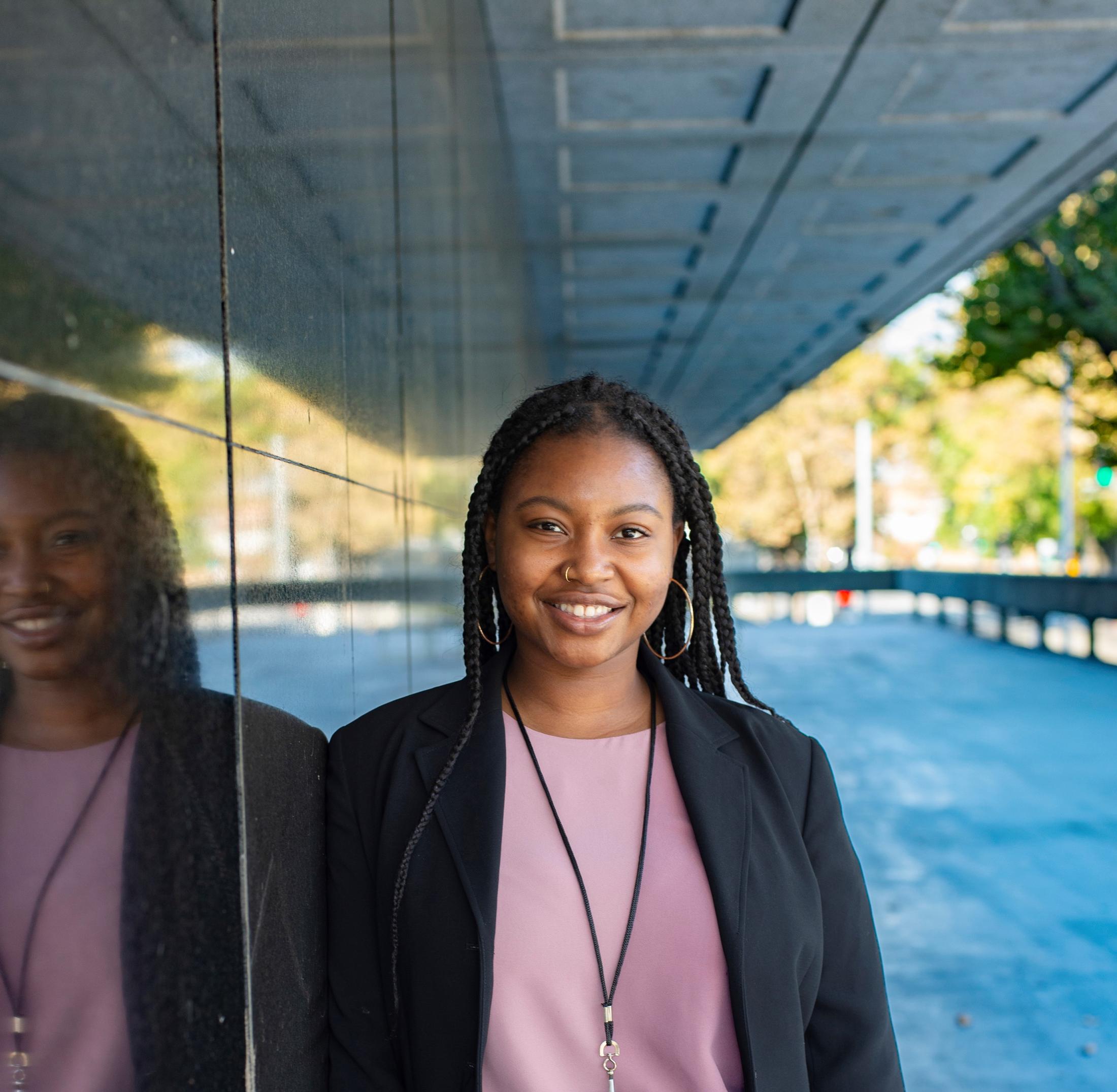 Photo of UC Davis alumna Valencia Scott standing outside next to a large window.