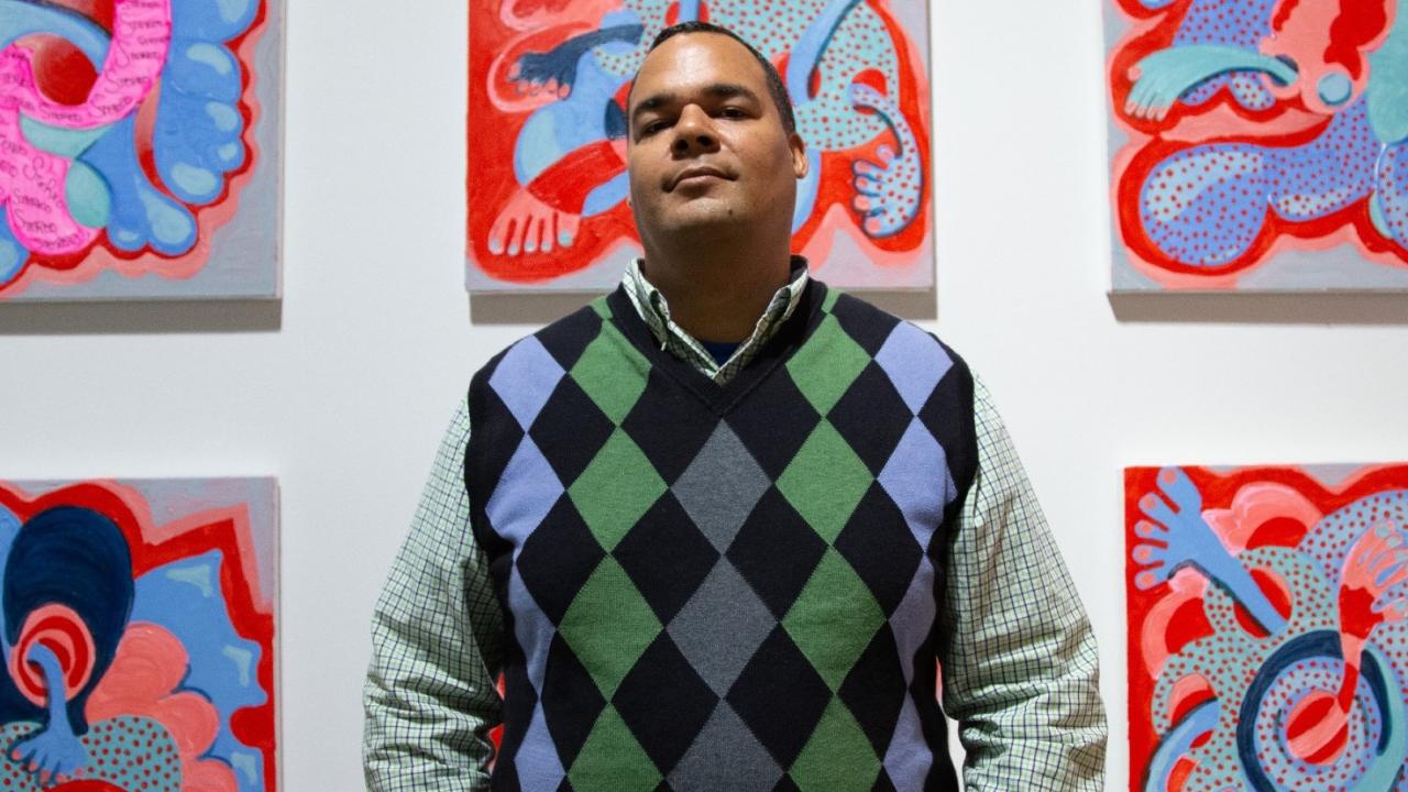 Photo of Tavarus Blackman with a group of his paintings 