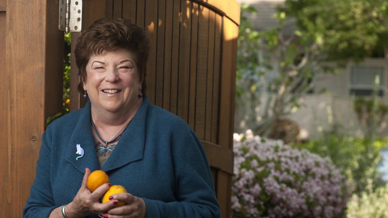 Photo: Eastin, with oranges in hands, standing in front of her garden gate