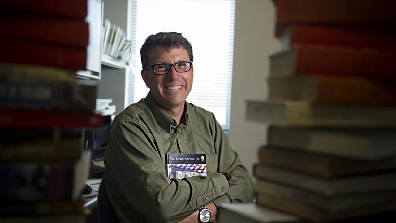 Gregory Downs, associate professor of history, sits among his research materials on the Reconstruction Era. (Gregory Urquiaga/UC Davis). Photo of historian in his office
