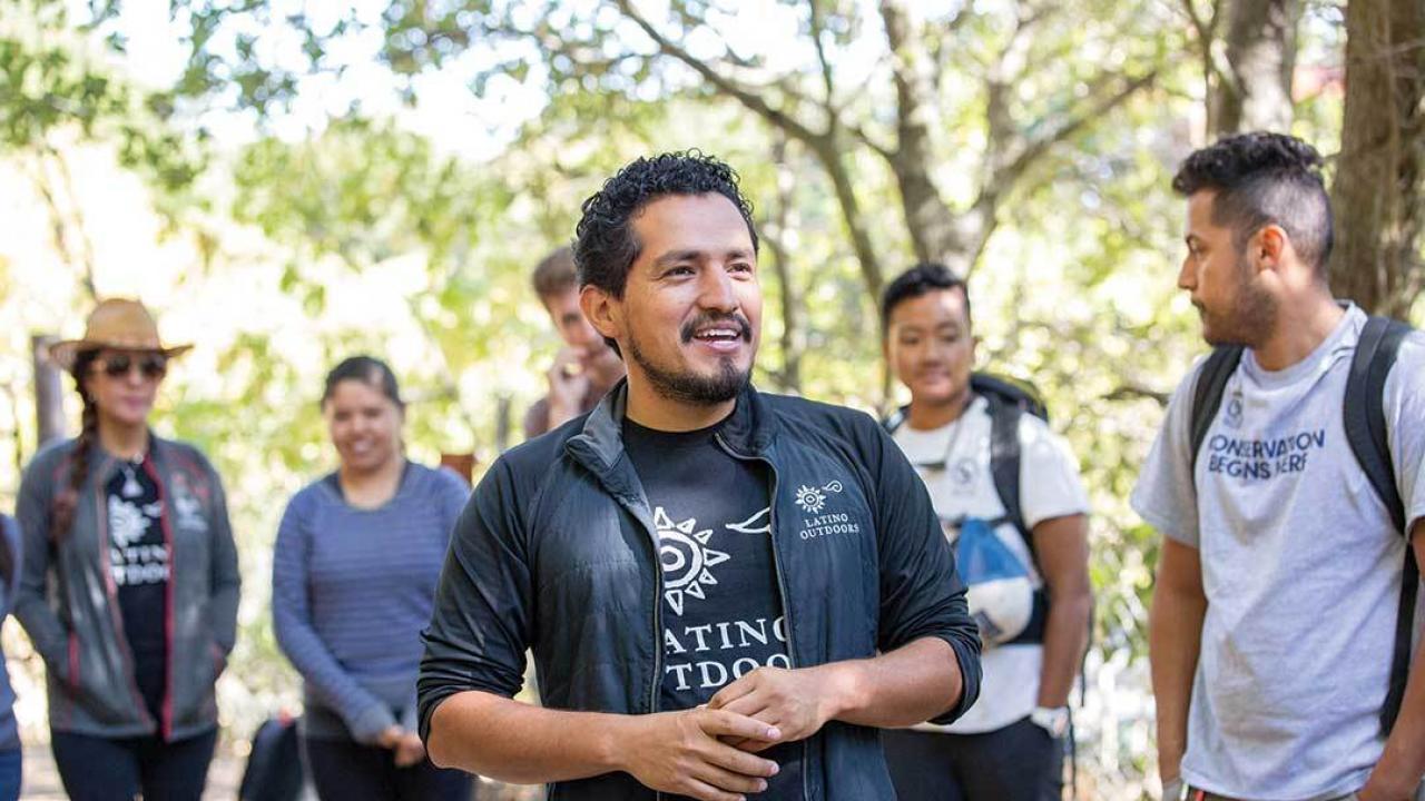 UC Davis history alumnus José González is the founder of Latino Outdoors. (Courtesy photo) Photo of Gonzalez outdoors with a group of hikers behind him.