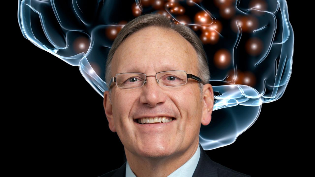 Portrait photo of UC Davis cognitive neuroscientist Ron Mangun with image of brain behind him.