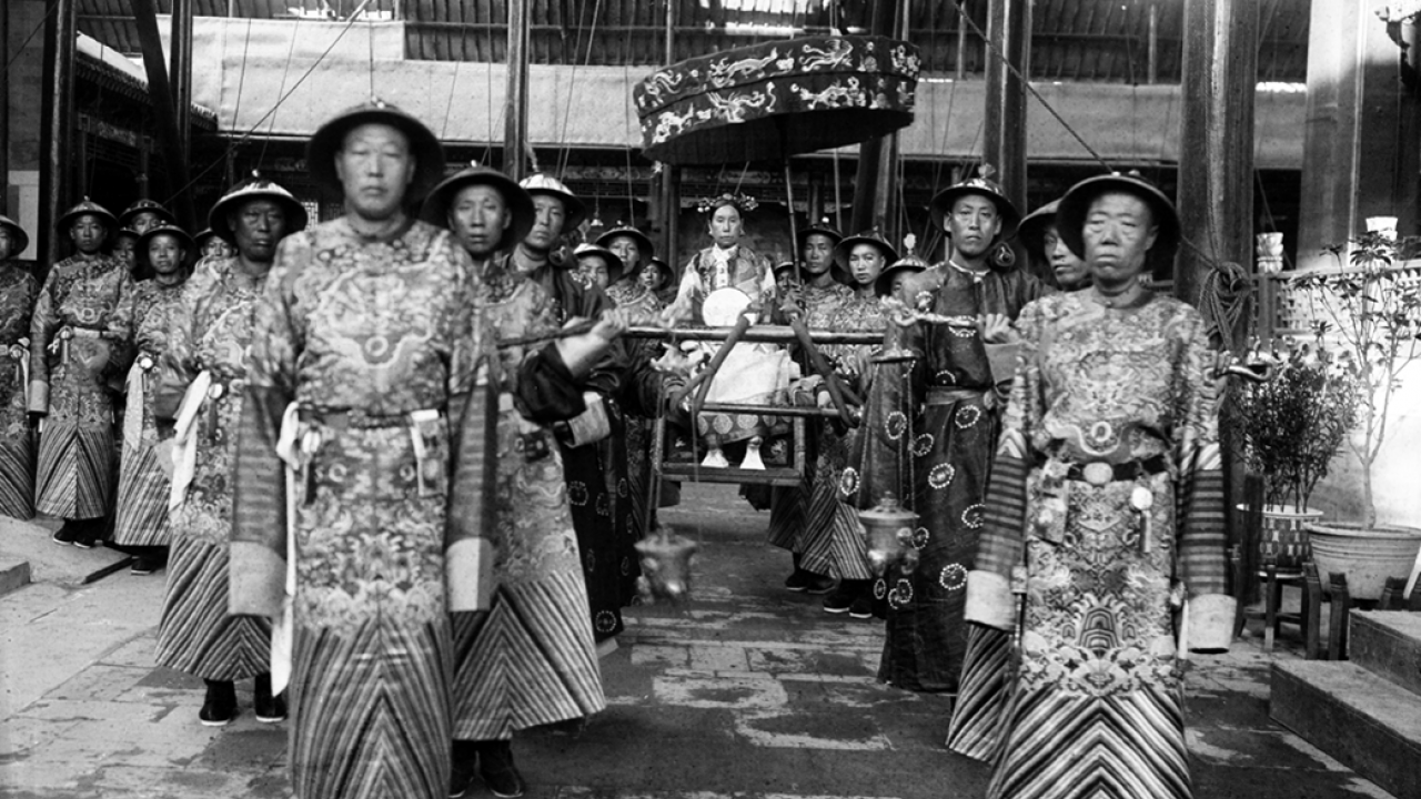 historic photo of eunuchs in two lines carrying empress dowager in sedan chair 