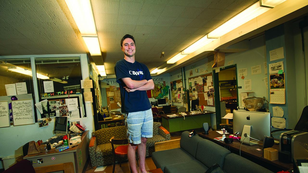 Scott Dresser, a political science/economics double major and editor in chief of the California Aggie, stands in the Aggie office in basement of Freeborn Hall. (Photo by Karin Higgins/UC Davis) Photo of smiling editor in Cal Aggie newsroom