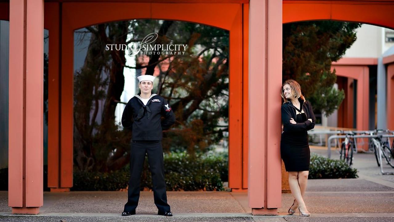 Dan and Kate (O'Rear) McCoy took their 2011 engagement photos near the UC Davis Art Building, where they first met after class in 2005. (Photo by Jenny Nguyen ’00/Studio Simplicity Photography) Photo of man in sailor uniform and woman smiling at him