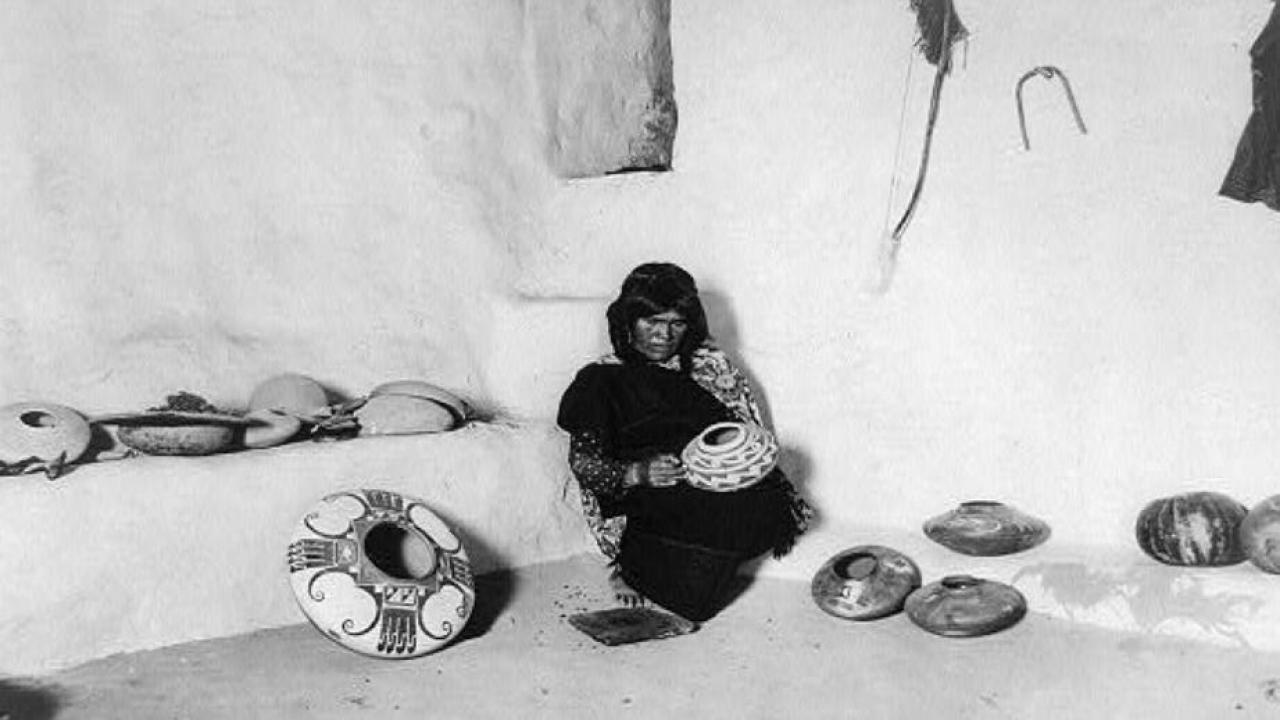 Archival photo showing woman decorating pots.