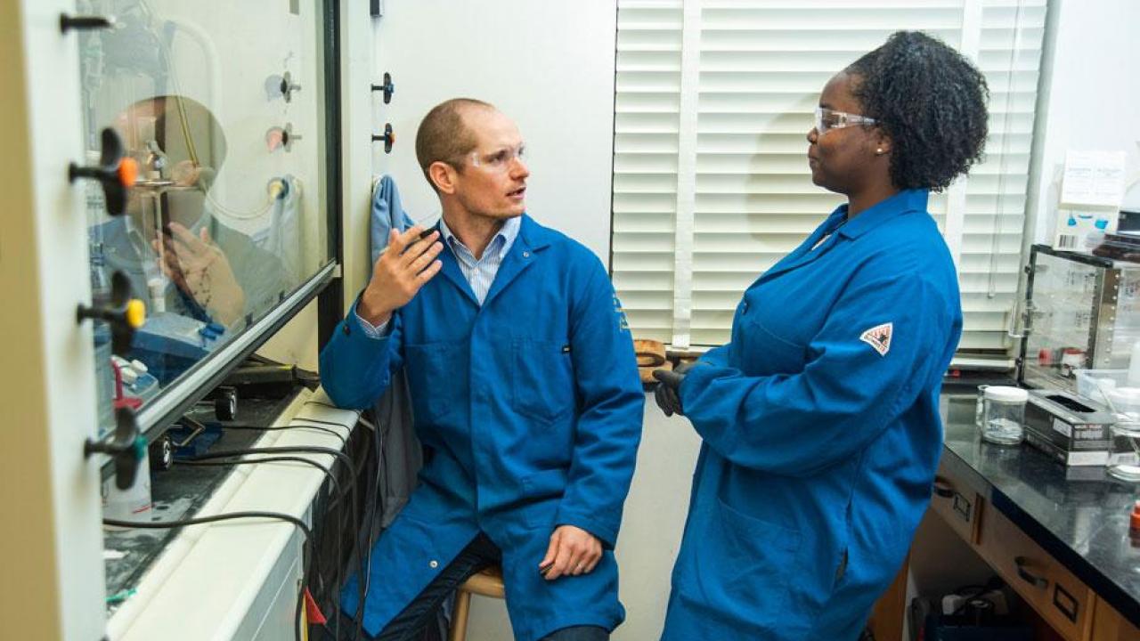 David Olson, assistant professor of chemistry, in his lab, speaking with Alaysia Madison, a chemistry student visiting from Xavier University.