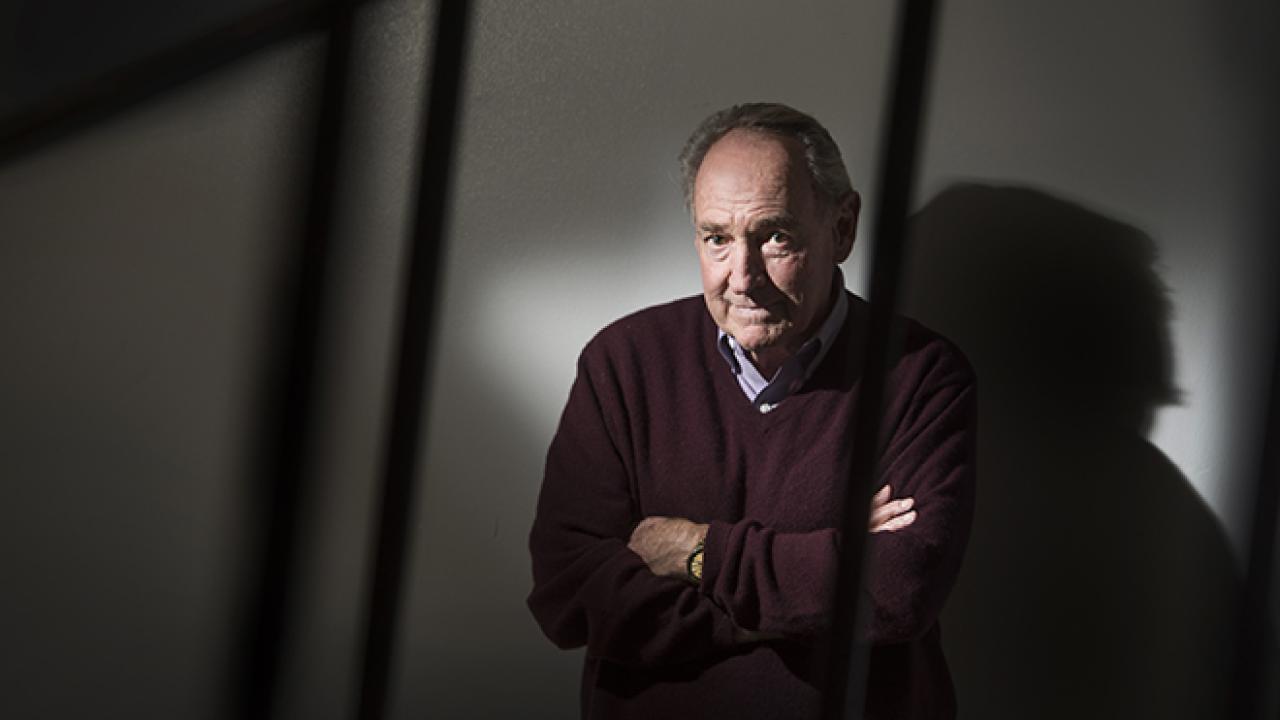 Photo: Professor standing in shadows of a stairrail