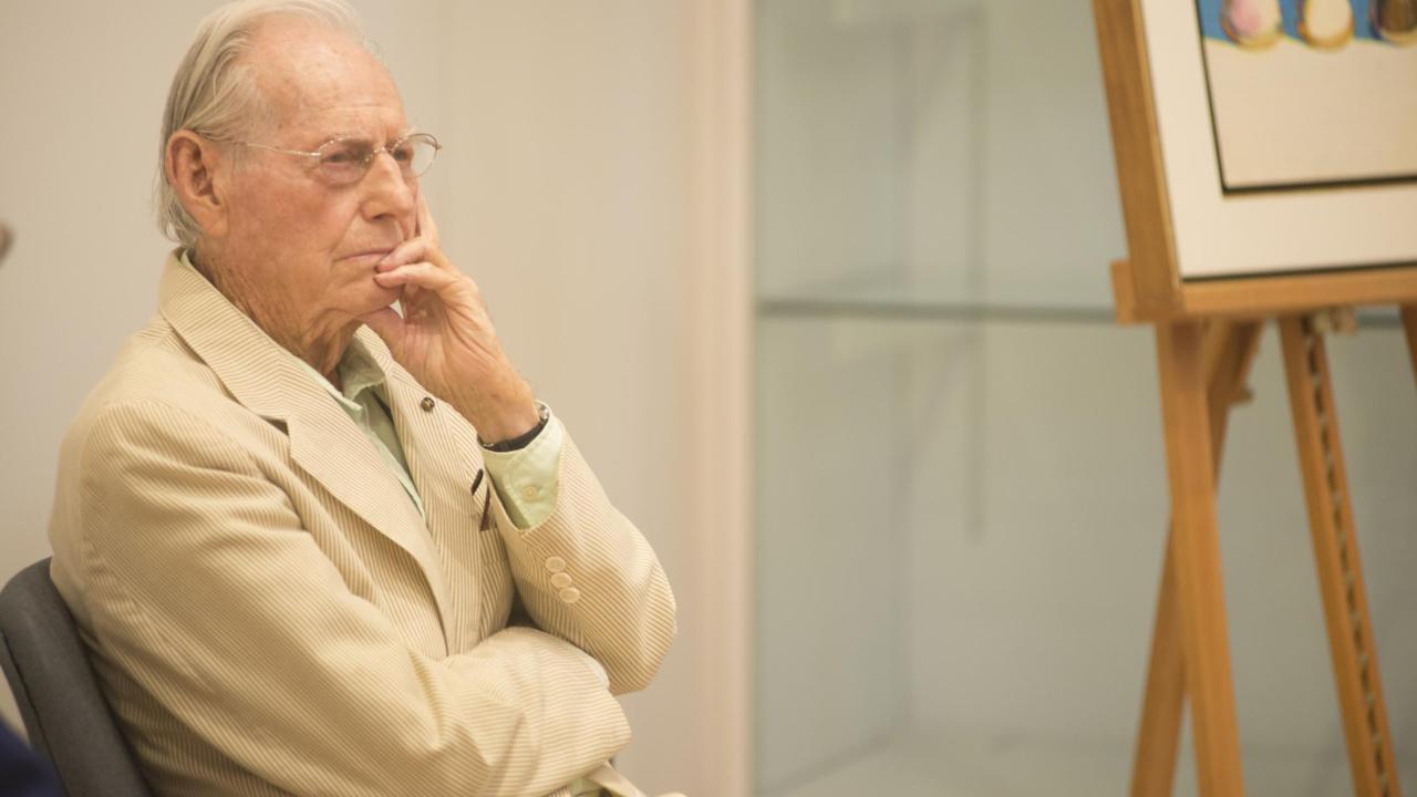 Seat Older man with gray hair with glasses, hand on chin, wearing tan suit