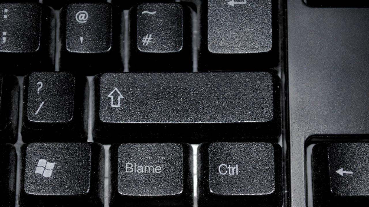 computer keyboard with word "blame" on shift key