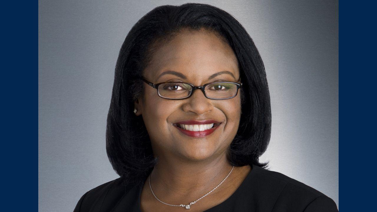 Women with dark hair mid neck straight, dark sop, glasses, smiling