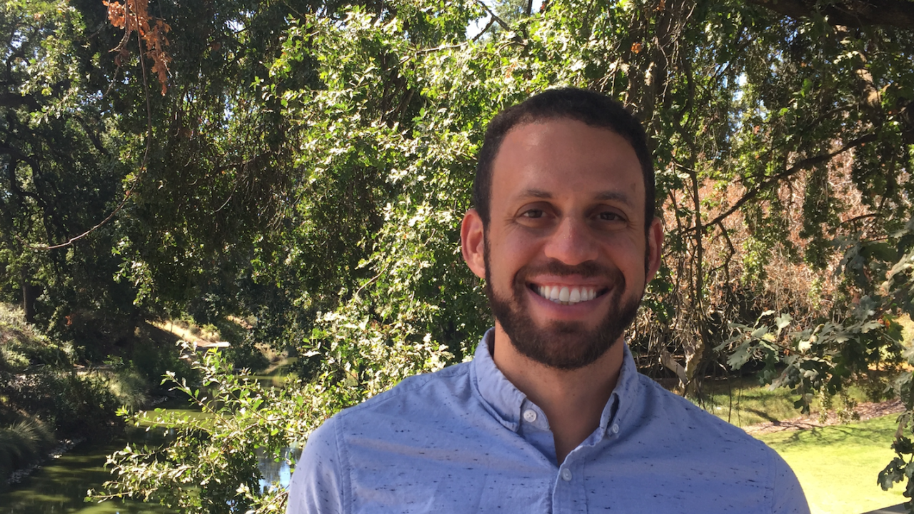 Photo of David Gold, assistant professor of geobiology, standing in front a tree in the UC Davis Arboretum.