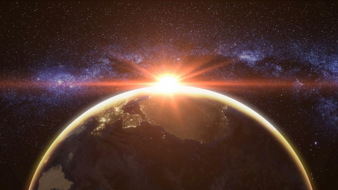 sun beams flare behind planet Earth