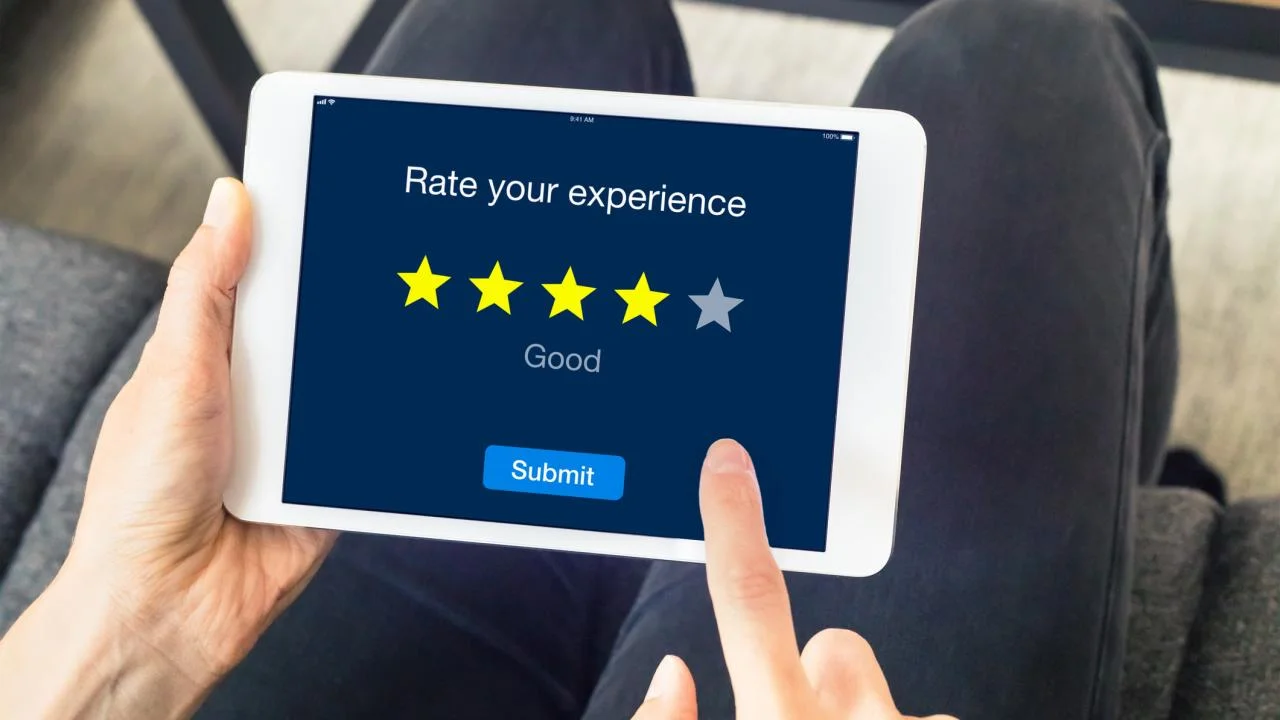 A close up of an Ipad on someone's lap with the screen having text that says "Rate your Experience"