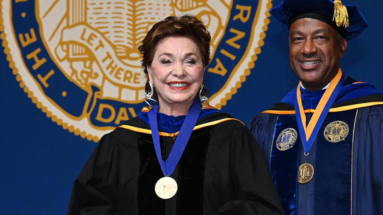 Maria Manetti Shrem wearing UC Davis Medal with Chancellor Gary S. May smiling on right at 2023 Commencement Ceremony with UC seal in background