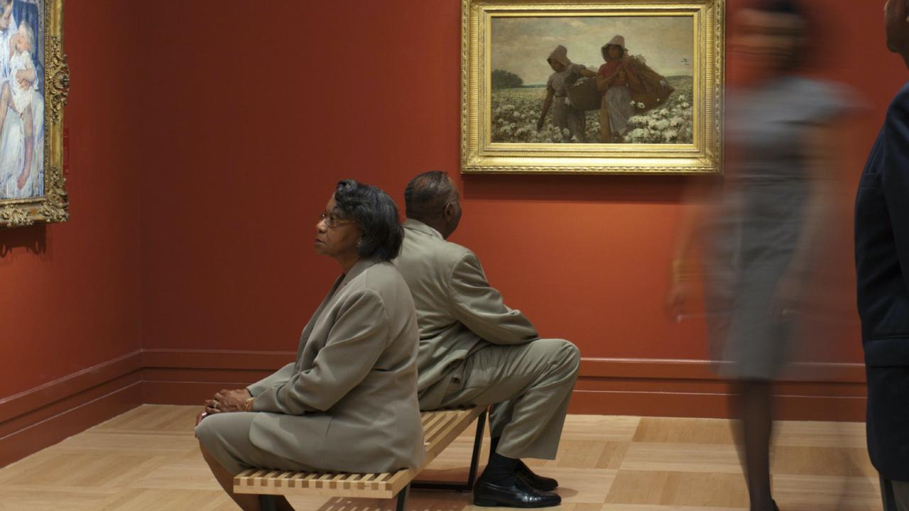 photo of people in art gallery looking at paintings
