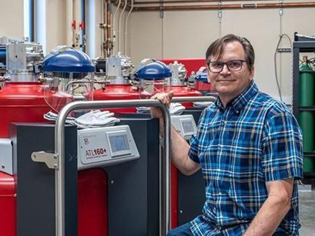 Peter Klavins poses in front of a helium tank.