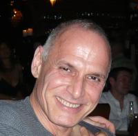 man with short cropped gray hair, head titled smiling