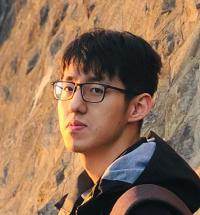 Yuxuan Zhang stands in front of a cliff.