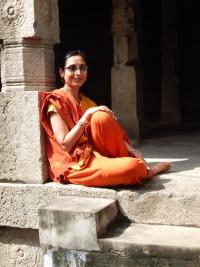 Photo of Archana Venkatesan, religious studies professor seated at a stone building in India.