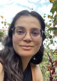 photo of a woman with glasses in a gardenwith flowers behind her 