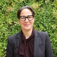 woman with dark hair, glasses, dark jacket and blouse