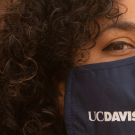 Photo of young woman wearing a face mask with UC Davis printed on it.