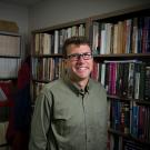 Photo of historian Gregory Downs standing in front of bookshelves