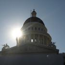 State capitol dome in Sacramento, with sun behind. 