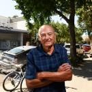 Photo of Bob Dunning with arms folded, standing on downtown Davis sidewalk, Varsity Theater, bikes and parked cars in background.