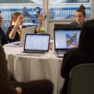 Photo of students talking around table with laptops
