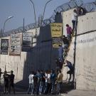 People climbing over barrier in Palestine