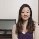 Photo of UC Davis graduate student in front of her desk, computer behind her. 