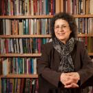 Portrait photo of UC Davis professor sitting in front of a wall of books.