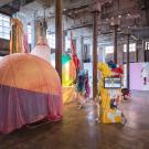 Large pieces of colorful artwork are displayed in a giant warehouse setting 