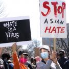 Two protesters, wearing face masks and shields, hold up signs that read #StopAsianHate and Hate is a Virus