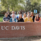 A group photo of ASPIRE students in front of a brick wall with UC Davis on the front of it.