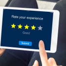 A close up of an Ipad on someone's lap with the screen having text that says "Rate your Experience"