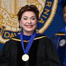 Maria Manetti Shrem wearing UC Davis Medal with Chancellor Gary May smiling on right at 2023 Commencement Ceremony